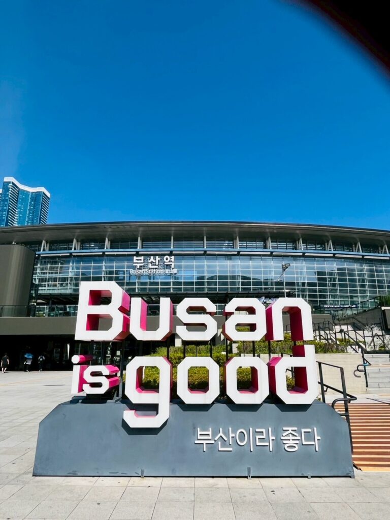 韓国・釜山駅前に設置された『Busan is good（釜山は良い街）』のモニュメント。青空と近代的な駅舎を背景にフォトスポットとして人気。