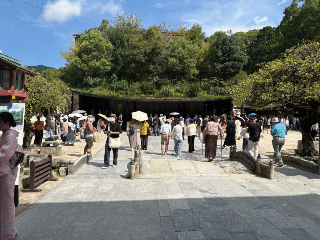 太宰府天満宮の拝殿前。緑に覆われた屋根の建物と広い境内には、多くの参拝客が行列を作り賑わっている