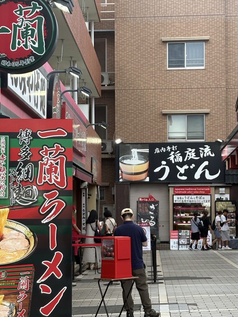太宰府参道にある一蘭ラーメンと稲庭流うどんの店舗前。観光客が並ぶ人気グルメスポットの様子