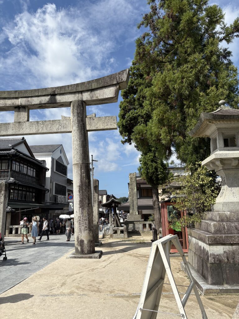 太宰府天満宮参道入口に立つ石造りの鳥居。両側には土産物店が並び、多くの観光客が訪れている