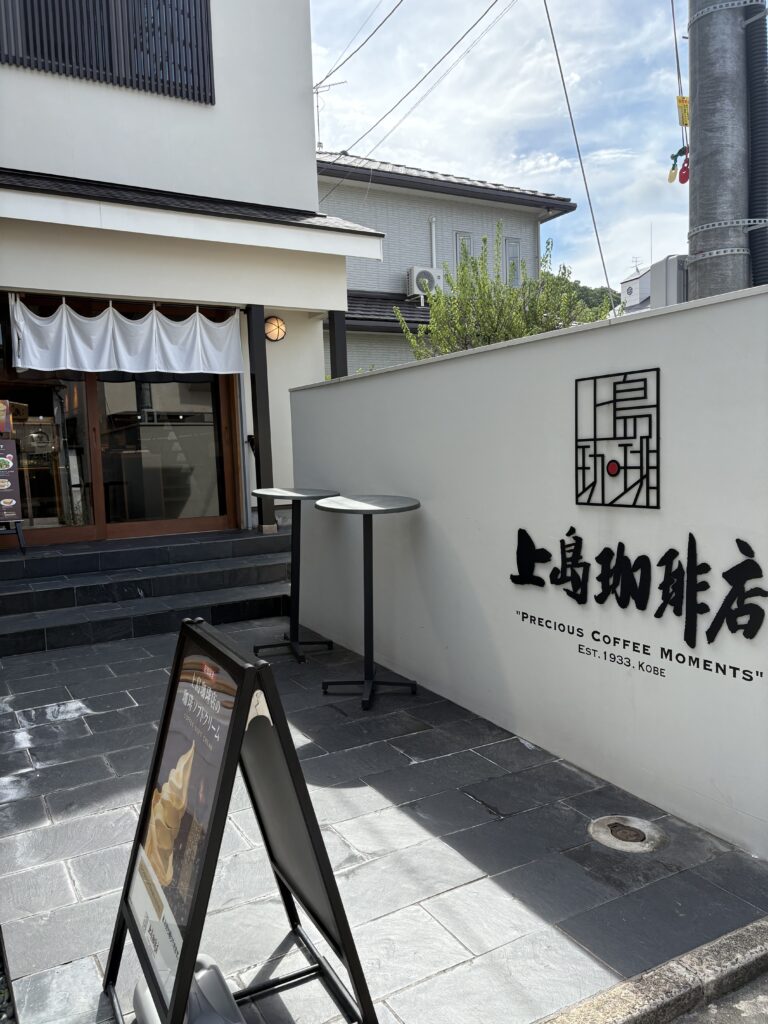 太宰府天満宮にある上島珈琲店の外観。白壁にシンプルなロゴと、入り口にのれんが掛かる落ち着いた雰囲気のカフェ