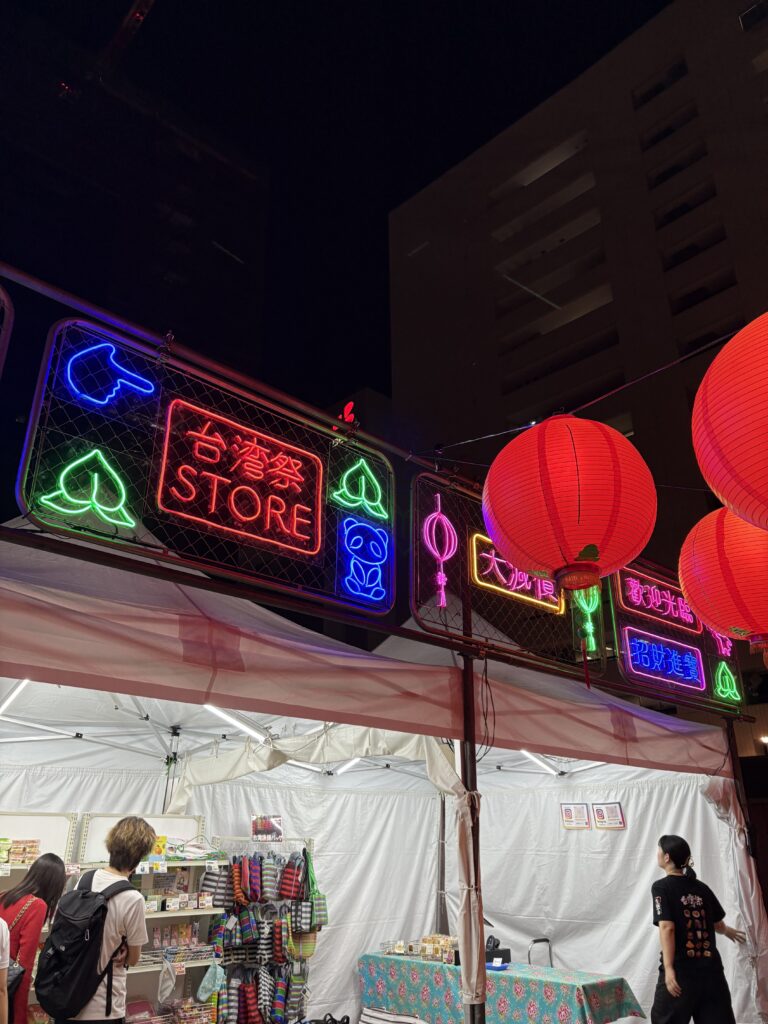 台湾祭 in 福岡2025の物販ブース。ネオン看板と赤提灯が灯る夜の会場の様子
