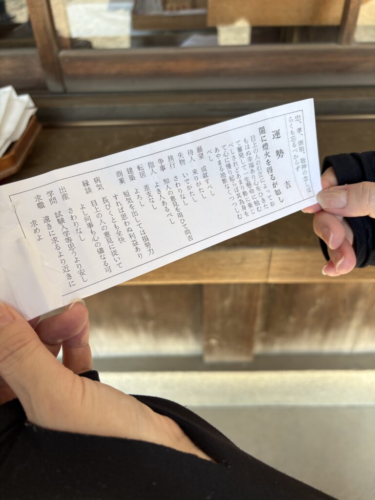 「吉」と書かれたおみくじを手にした様子