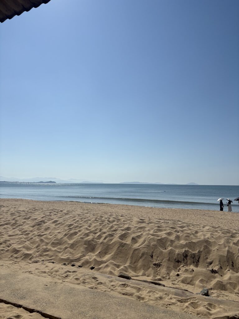 澄んだ青空とやわらかな波が広がる福間海岸の砂浜。秋でもあたたかい日差し。