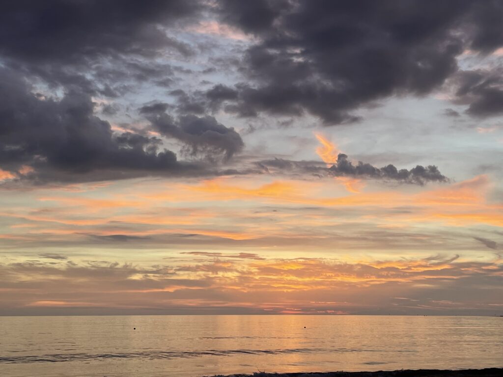 夕日に照らされた福間海岸。オレンジ色に染まる海と雲。